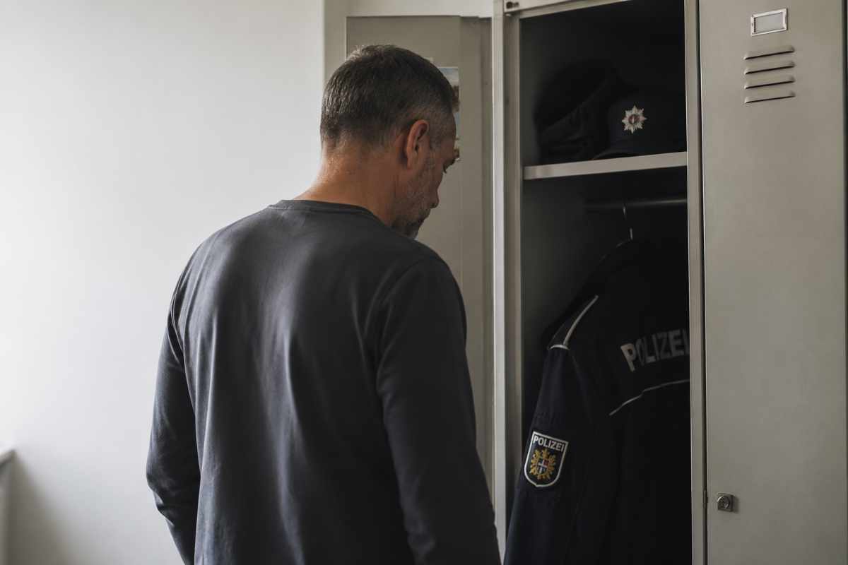 Polizeibeamter blickt still in einen halb geöffneten Spind mit Dienstkleidung – Symbolbild für Polizei Burnout und inneren Abschied vom Polizeidienst